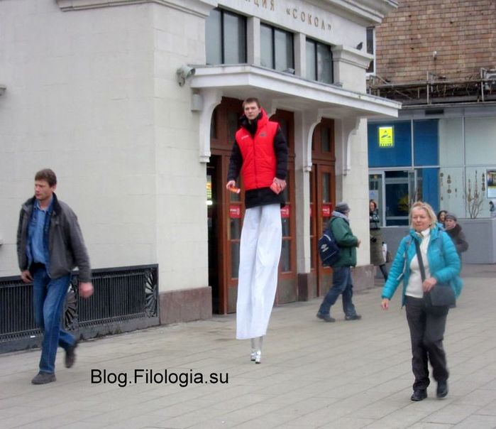 Юноша на ходулях раздает рекламные листовки у станции метро "Сокол" в Москве