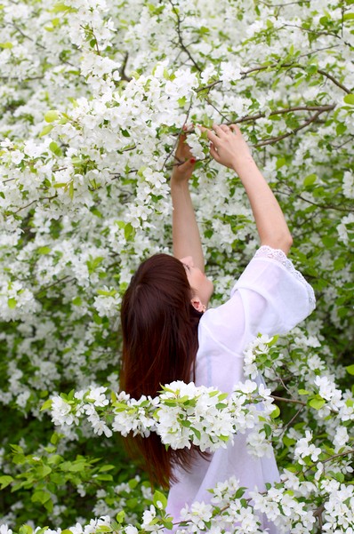 Фото девушки в цветущем саду со спины